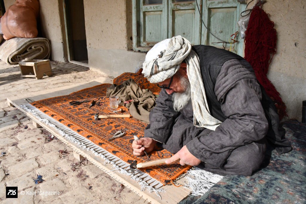 Elderly artisan finishing a woven carpet