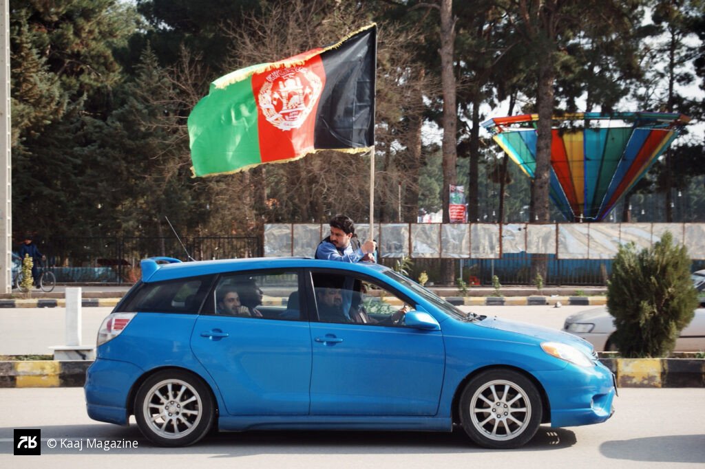 Afghan flag flying from a blue car