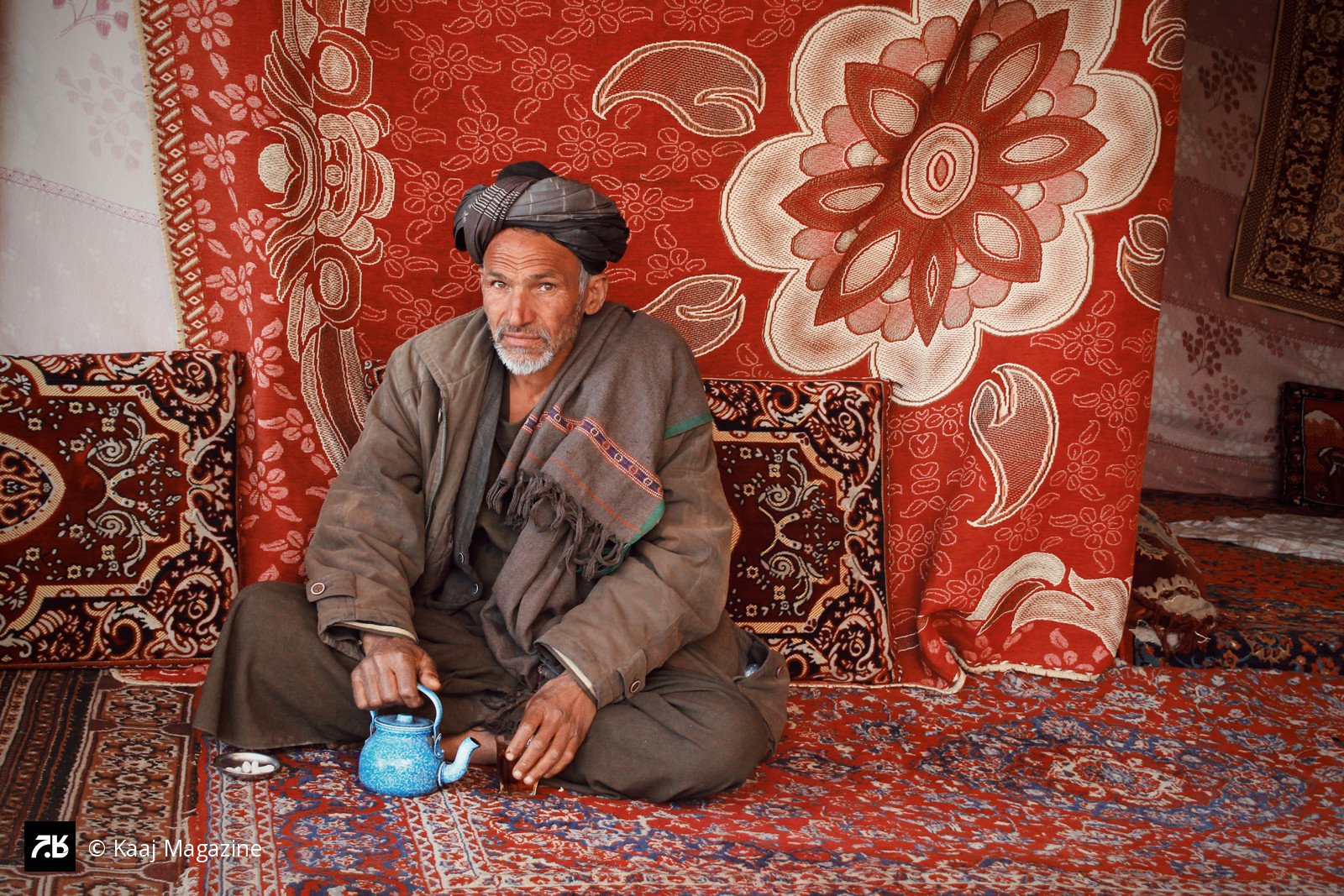 Man with a blue teapot on a rug