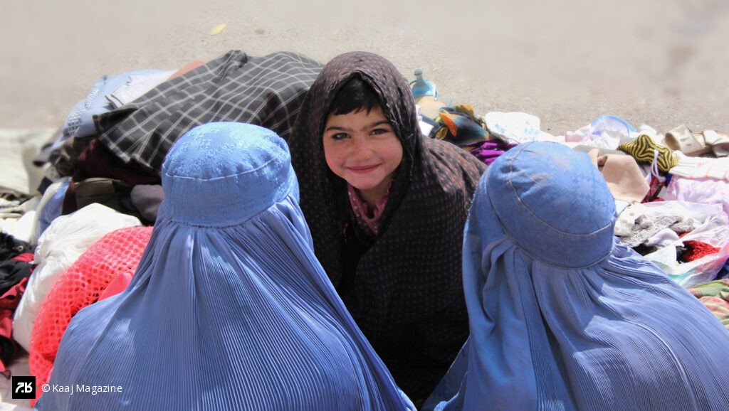 Smiling little girl between two blue burqas